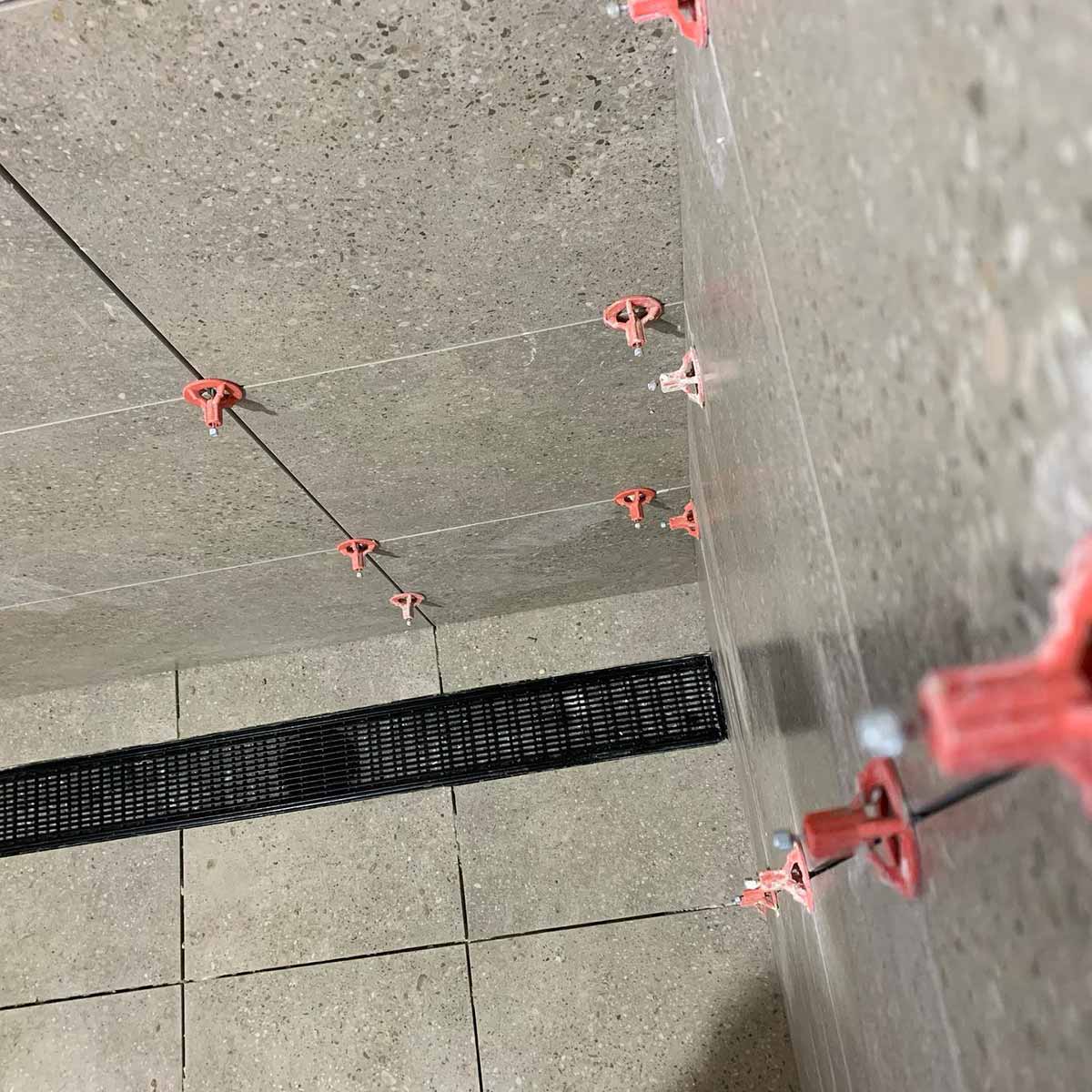 ATR Tile Leveling System use in a shower on a Ceramic Tile with Black Linea rain and showing the spindle attached in a Cross Pattern