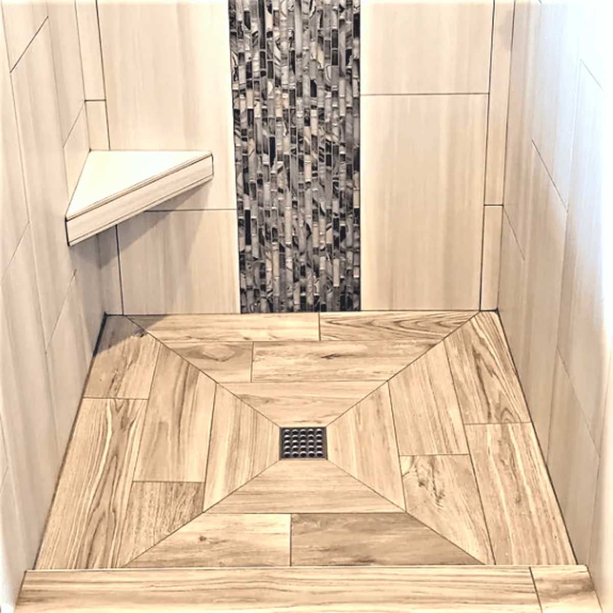 Modern shower with glass door, tiled walls, and a bench with a towel and Ebbe Square Shower Drain Grates