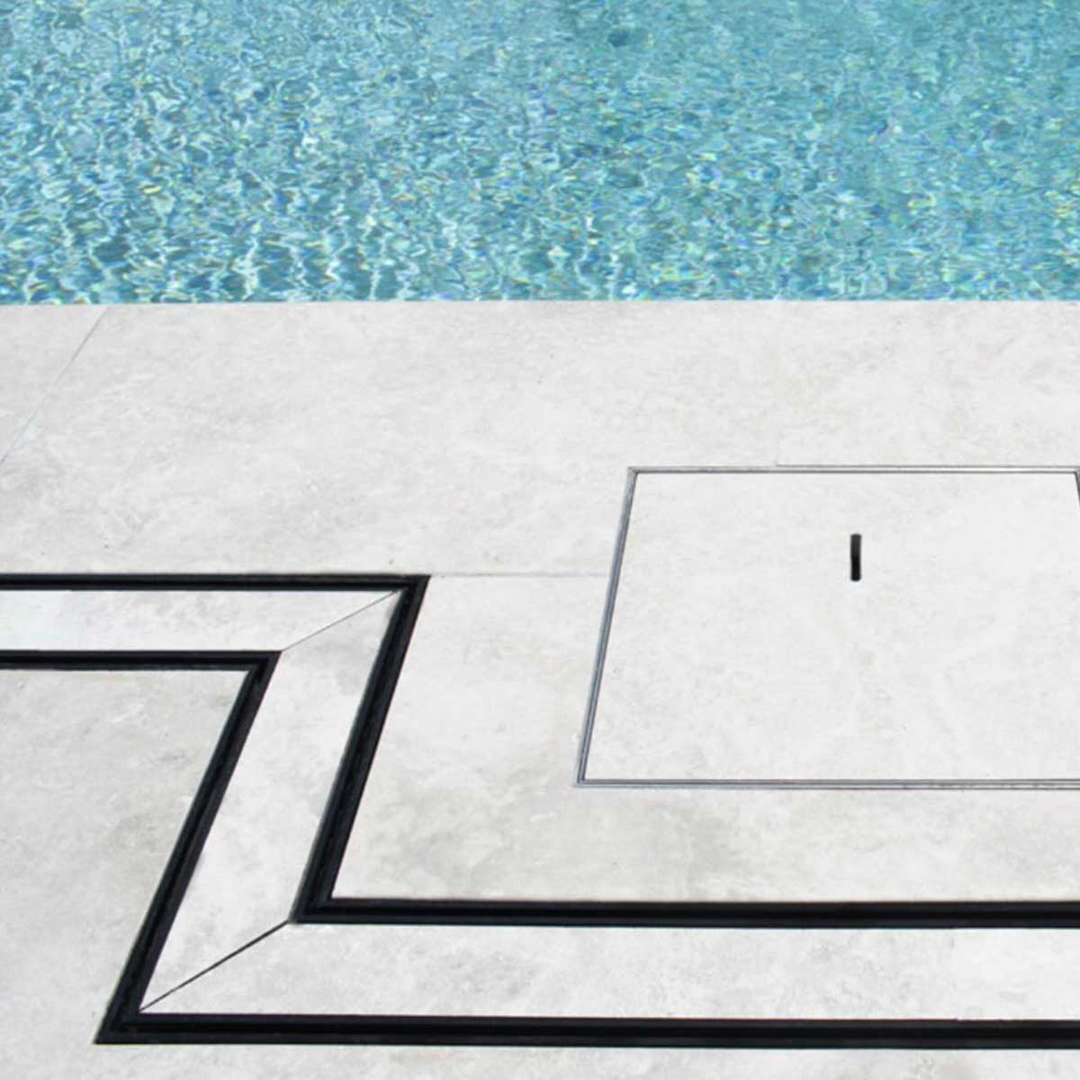 Close-up of a tiled floor with Lauxes Grates Custom shower drain Tile Insert in Midnight Black around the pool
