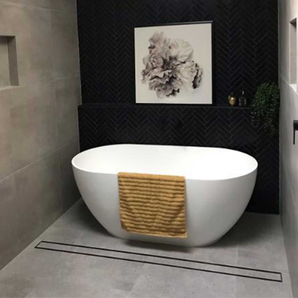 Close-up of a tiled floor with Lauxes Grates Custom shower drain Tile Insert in Midnight Black