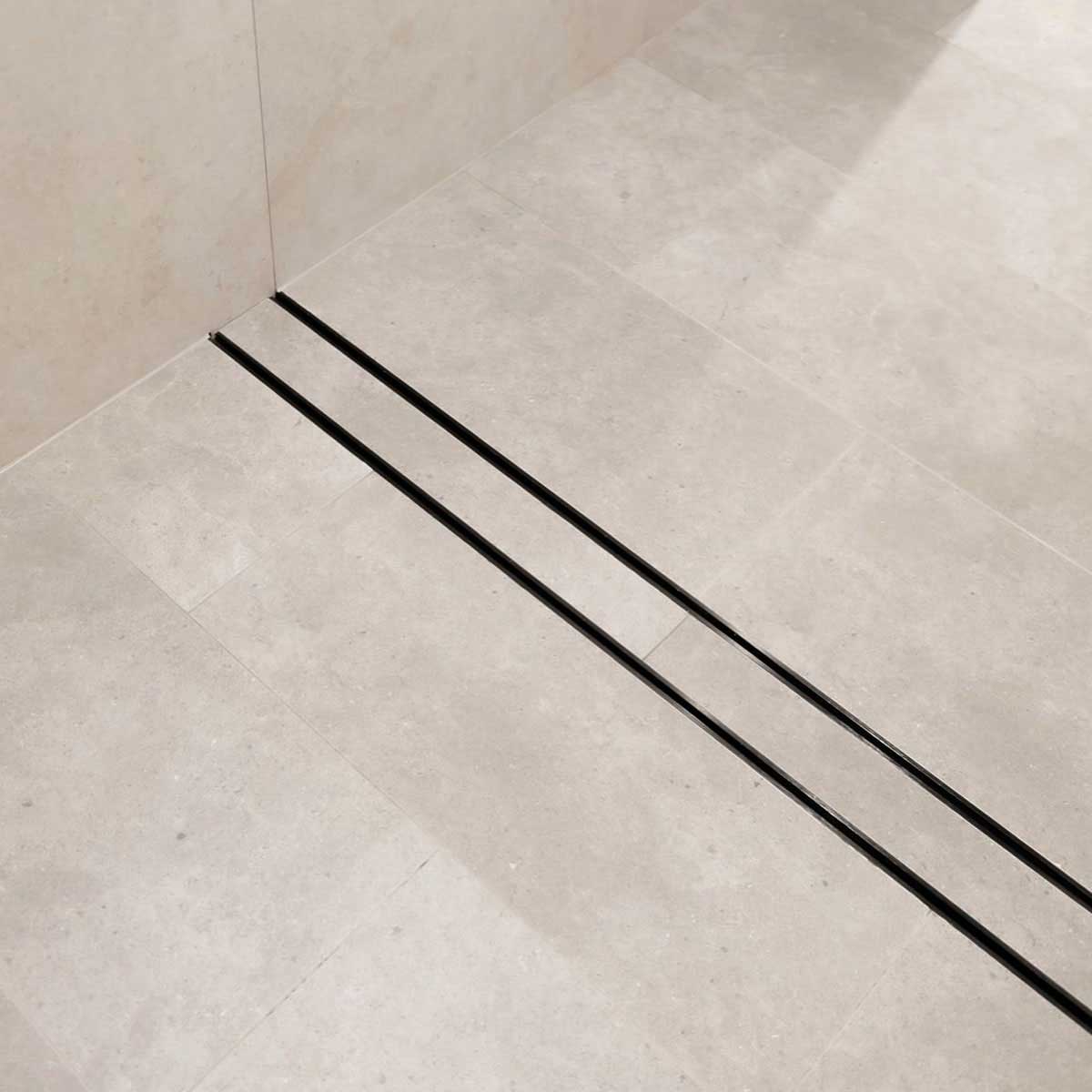 Close-up of a tiled floor with Lauxes Grates Custom shower drain Tile Insert in Midnight Black