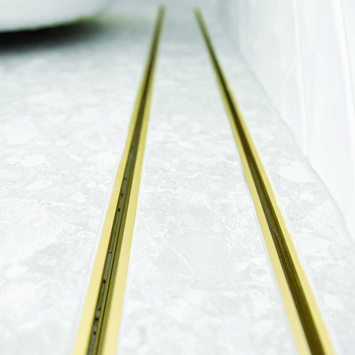 Close-up of a tiled floor with Lauxes Grates Custom shower drain Tile Insert in Matte Gold finish