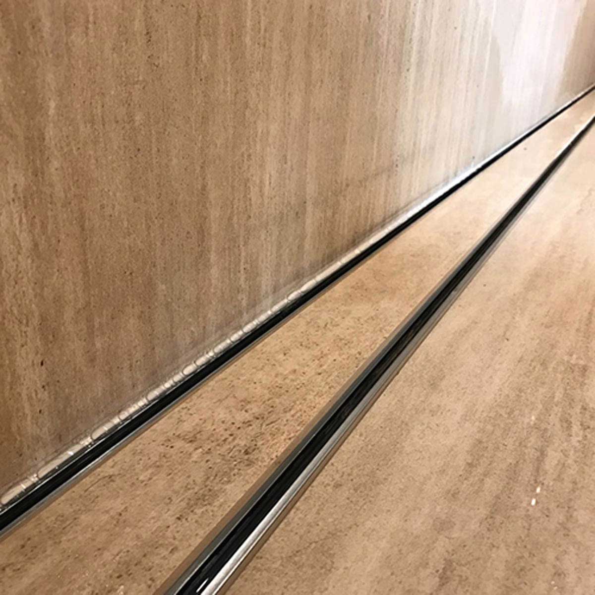 Close-up of a tiled floor with Lauxes Grates Custom shower drain Tile Insert in Silk Silver finish