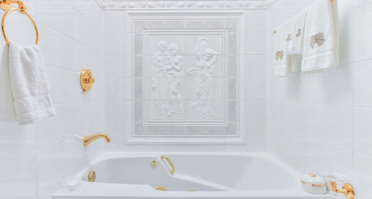 Luxurious bathroom with white tiles, gold fixtures, and towels.