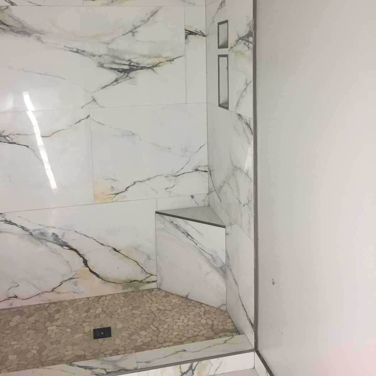 Marble-patterned shower enclosure with tiled walls and floor where the PreFormed Ready to Tile Shower Pan