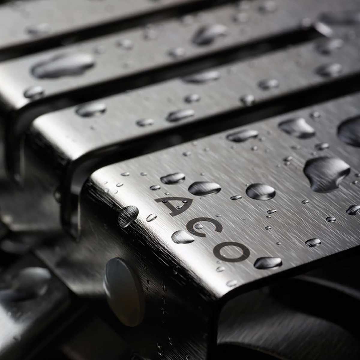 Close-up of Quartz by ACO Piano grate polished chrome linear shower drain with precision stainless steel slots