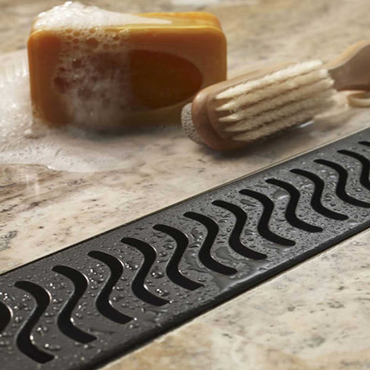 QuARTz Linear Shower Drain with Flag Grate - Oil Rubbed Bronze Installed in shower floor with soap and brush