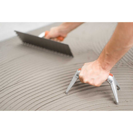 Person using a trowel to spread a substance on a flat surface