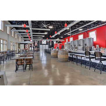 Large industrial-style room with tables, chairs, and beer-themed decor.
