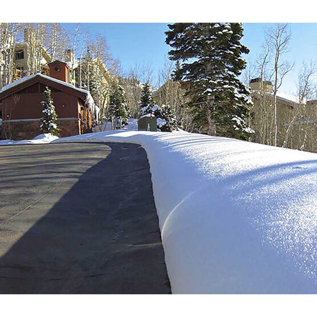Snow-covered street with buildings and trees in the background