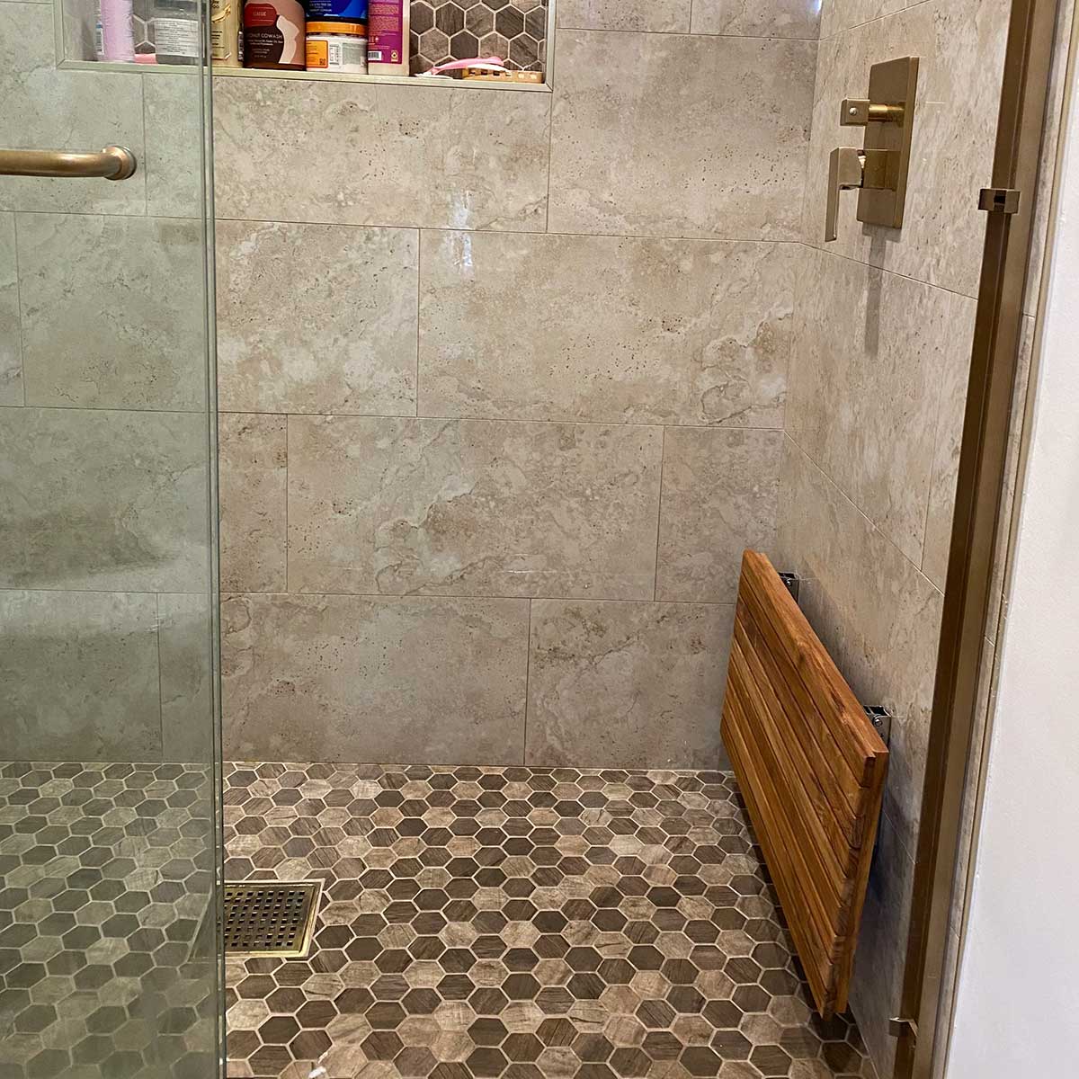 Fold down teak shower seat in luxury bathroom