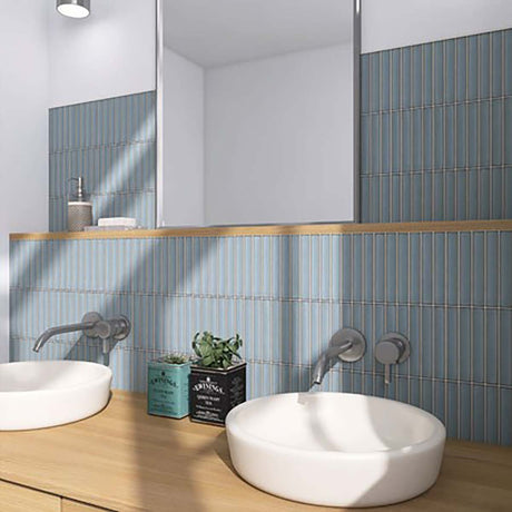 Bathroom with two white sinks, blue tiled walls, and a wooden countertop.