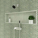Bathroom setting with a shower head, soap dispenser, and plant against a Hexagon Porcelain Mosaic Tile - Sage Green