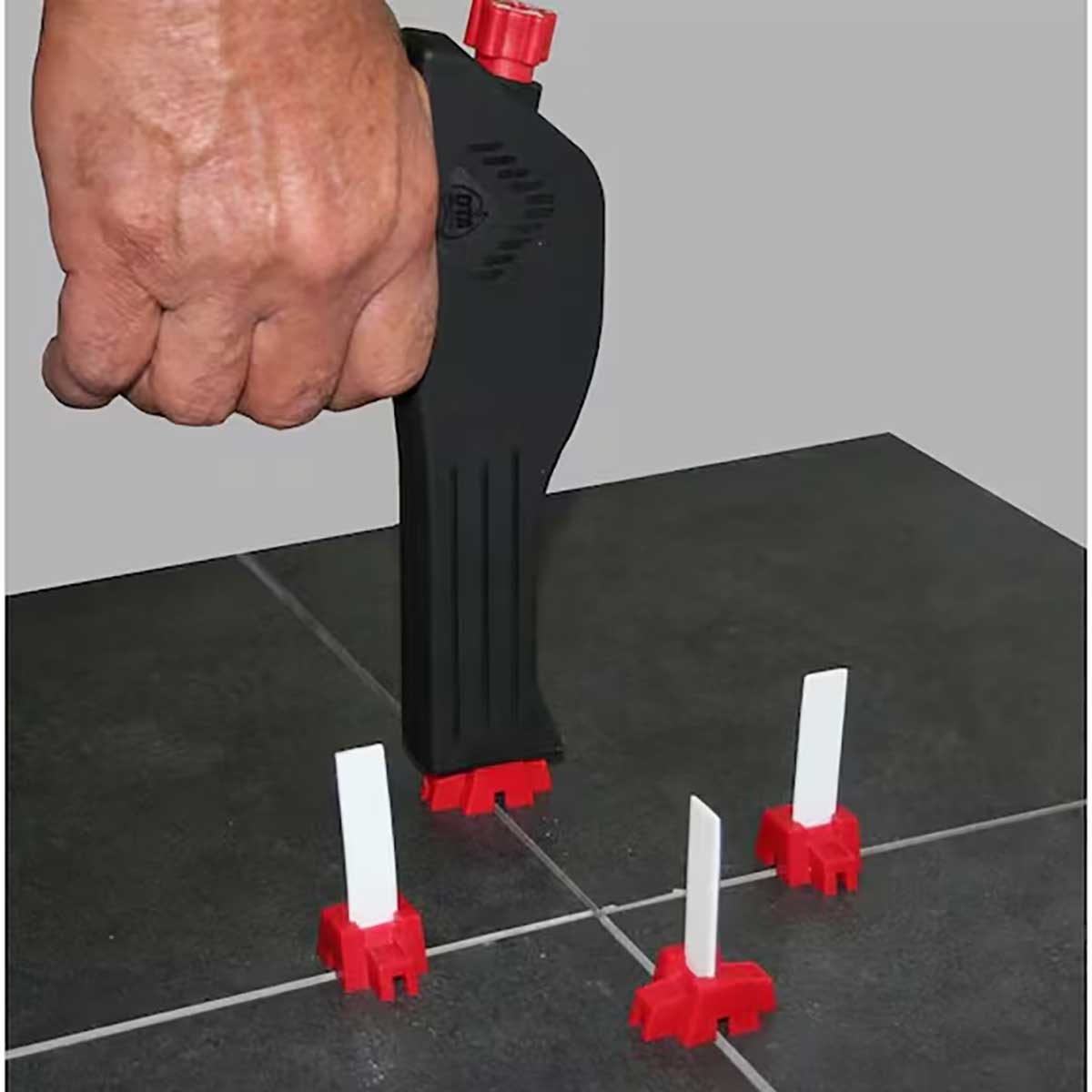 Hand using a DTA tile leveling system tool GUN on a tiled floor