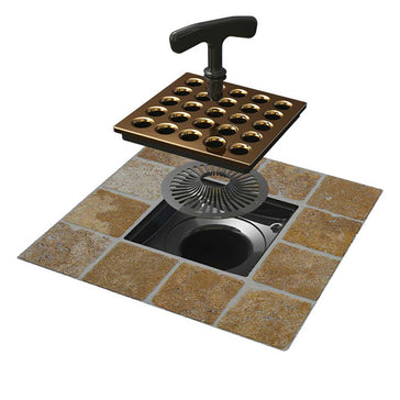 Ebbe Pro Square Shower Drain in gold finish with handle on a tiled floor