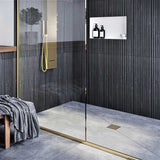 Modern shower with glass door, tiled walls, and a bench with a towel and Ebbe Square Shower Drain Grates