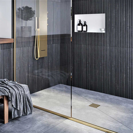 Modern shower with glass door, tiled walls, and a bench with a towel and Ebbe Square Shower Drain Grates