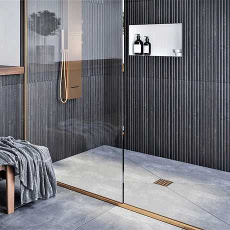 Modern shower with glass door, tiled walls, and a bench with a towel and Ebbe Square Shower Drain Grates Matte Black PVD 