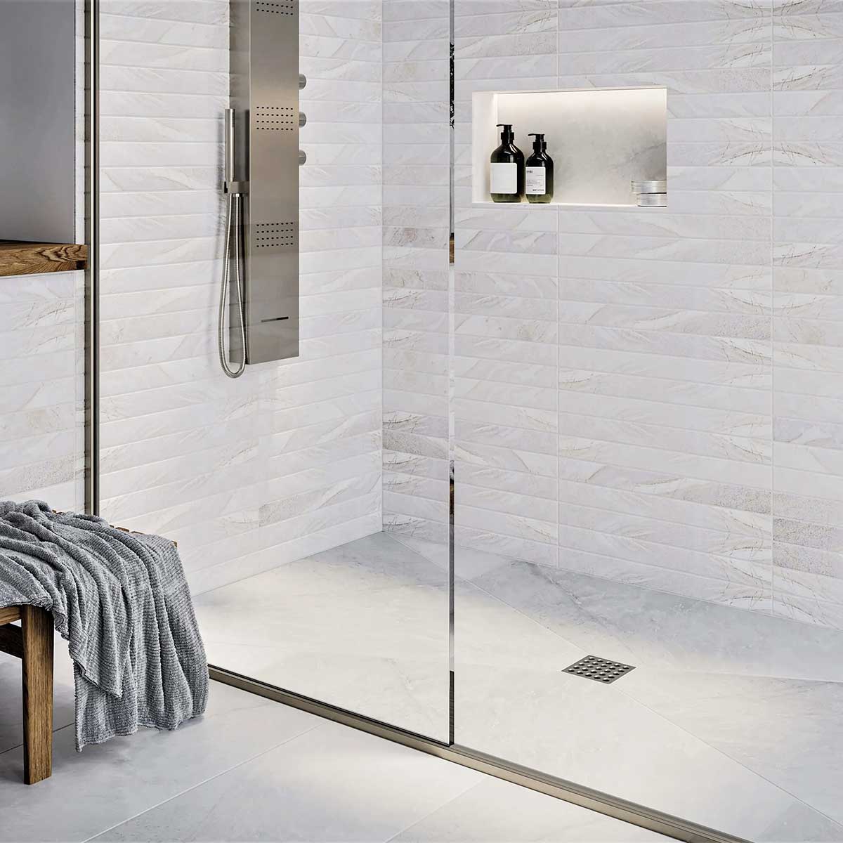 Modern shower with glass door, tiled walls, and a bench with a towel and Ebbe Square Shower Drain Grates Matte Black PVD 