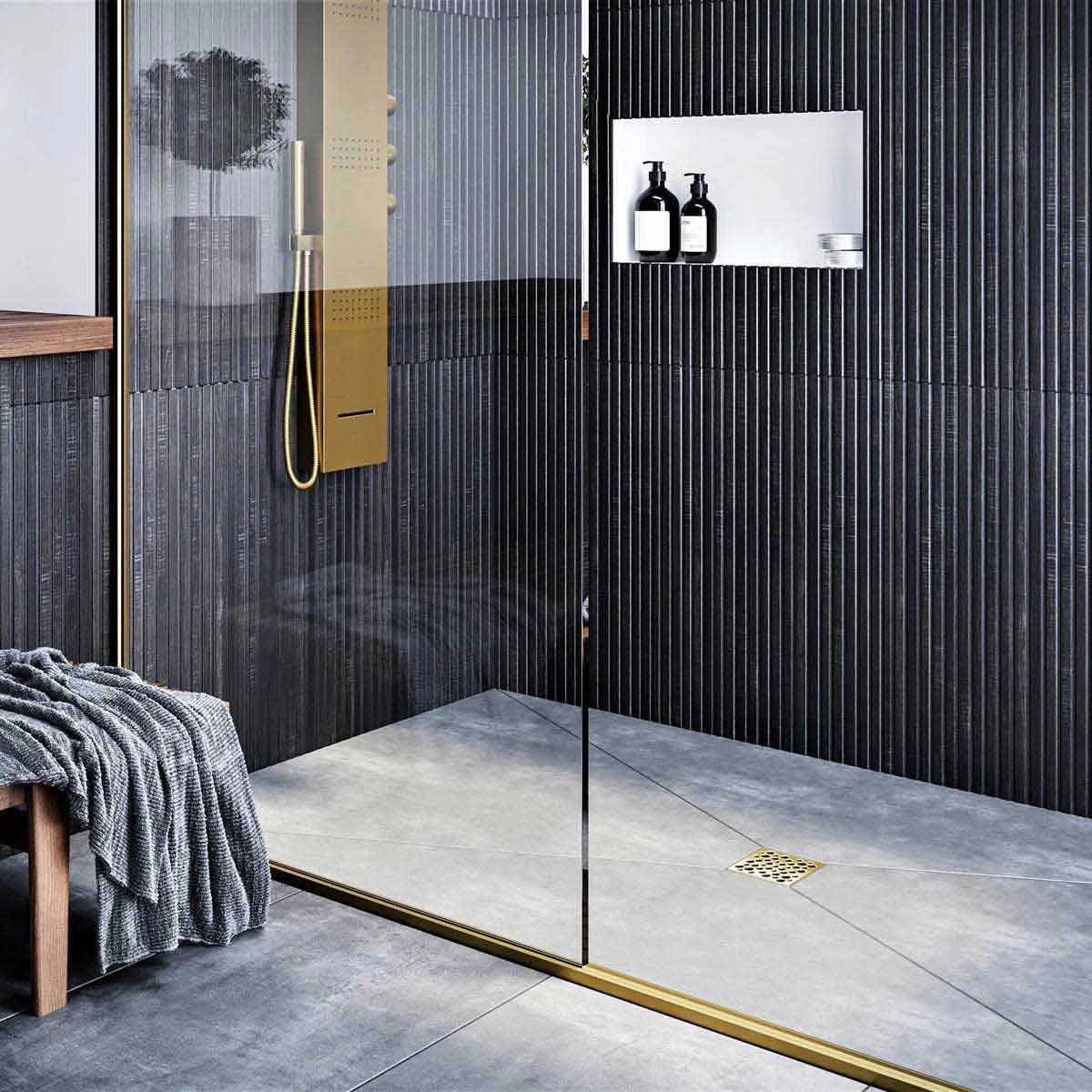 Modern bathroom with glass shower enclosure, black wall tiles, and gold fixtures with Ebbe Drains Unique Square Shower Drain Grate - Bubbles