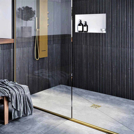 Modern bathroom with glass shower enclosure, black wall tiles, and gold fixtures with Ebbe Drains Unique Square Shower Drain Grate - Bubbles