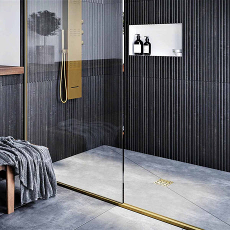 Modern bathroom with glass shower enclosure, black wall tiles, and gold fixtures with Ebbe Drains Unique Square Shower Drain Grate - Lattice