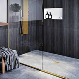 Modern bathroom with glass shower enclosure, black wall tiles, and gold fixtures with Ebbe Drains Unique Square Shower Drain Grate - Parallel