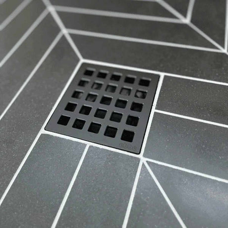 Ebbe Drains Unique Square Shower Drain Grate - Quadra Matte Black on a gray tiled floor