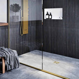Modern bathroom with glass shower enclosure, black wall tiles, and gold fixtures with Ebbe Drains Unique Square Shower Drain Grate - Twister