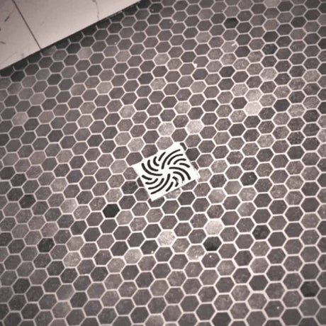 Hexagonal tile floor with a Ebbe Drains Unique Square Shower Drain Grate - Twister In brushed Nickel