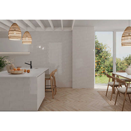 Modern kitchen with white island, wooden chairs, and Kaleidoscope 3x6 Handmade Ceramic Subway Tile - Light Grey Glossy Spanish Wall Tile