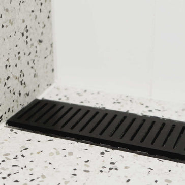 Lauxes Grates Custom Linear Shower Drain NeXT Generation Midnight Black on a terrazzo-patterned floor