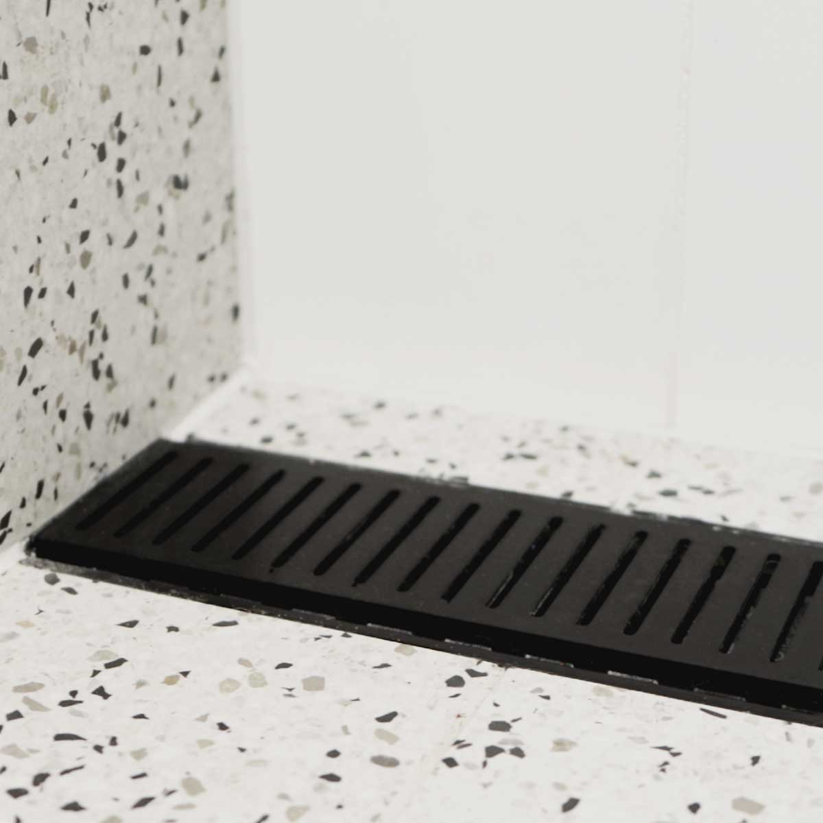 Lauxes Grates Custom Linear Shower Drain NeXT Generation Midnight Black on a terrazzo-patterned floor