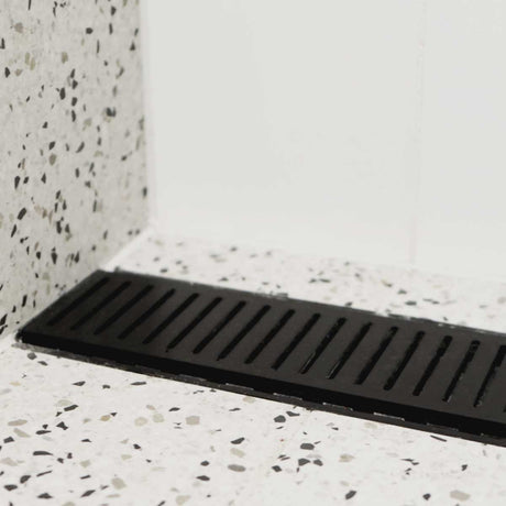 Lauxes Grates Custom Linear Shower Drain NeXT Generation Midnight Black on a terrazzo-patterned floor