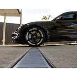 Black sports car approaching a Lauxes Grates Custom Linear Shower Drain NeXT Generation Midnight Black