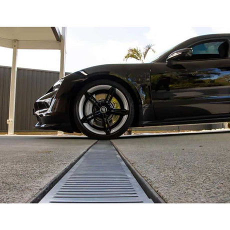 Black sports car approaching a Lauxes Grates Custom Linear Shower Drain NeXT Generation Midnight Black