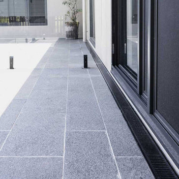 Gray tiled patio area with Lauxes Grates Custom Linear Shower Drain NeXT Generation Midnight Black