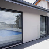 Modern house exterior with large glass windows overlooking a pool with Lauxes Grates Custom Linear Shower Drain NeXT Generation Midnight Black Installed
