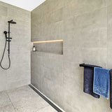 Modern shower with tiled walls, black fixtures, towels hanging on a rack and Lauxes Grates Custom Linear Shower Drain NeXT Generation Midnight Black