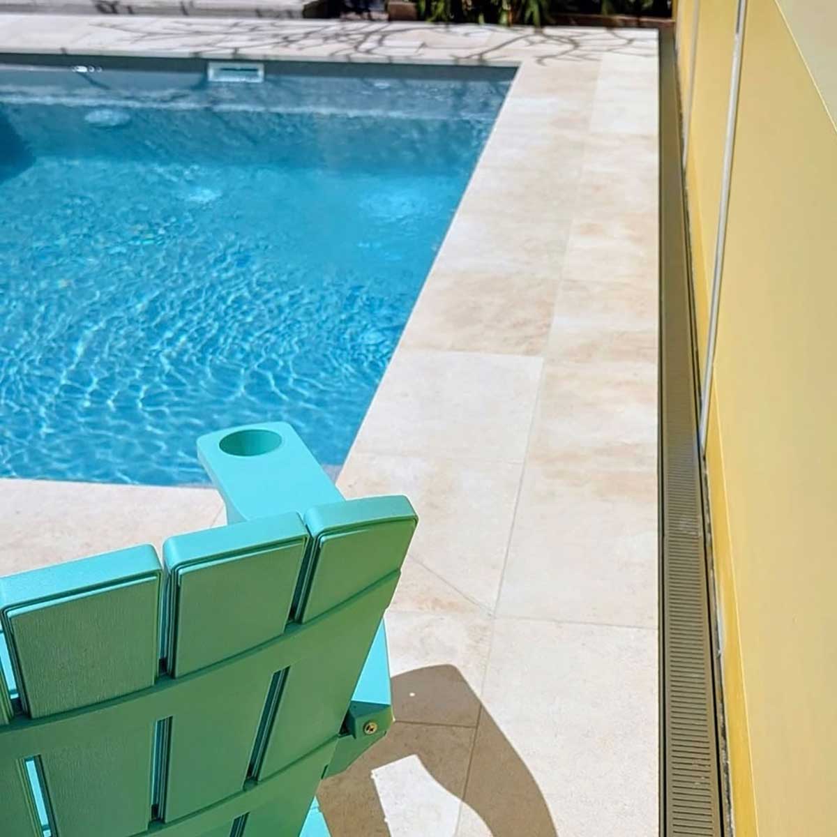 Lauxes Grates Custom Linear Shower Drain NeXT Generation - Matte Gold Installed around pool area with green plastic chair 