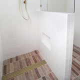 Bathroom shower with white tiled walls and a brown tiled floor with Lauxes Grates Custom Linear Shower Drain NeXT Generation - Matte Gold
