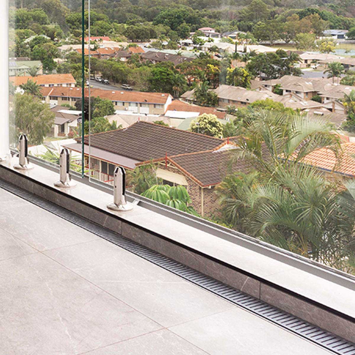 Glass railing system with a view of residential houses and greenery with Lauxes Grates Custom Linear shower Drain NeXT Generation - Silk Silver