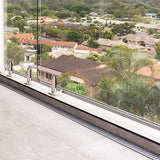Glass railing system with a view of residential houses and greenery with Lauxes Grates Custom Linear shower Drain NeXT Generation - Silk Silver
