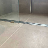 Tile shower floor with a Lauxes Grates Custom Linear shower Drain NeXT Generation - Silk Silver and glass wall