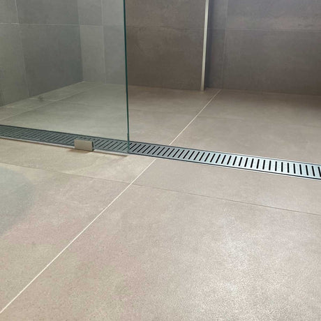 Tile shower floor with a Lauxes Grates Custom Linear shower Drain NeXT Generation - Silk Silver and glass wall