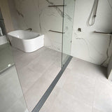 Modern bathroom with a freestanding bathtub and glass shower enclosure with Lauxes Grates Custom Linear shower Drain NeXT Generation - Silk Silver on floor tile