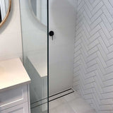 Close-up of a tiled floor with Lauxes Grates Custom shower drain Tile Insert in Midnight Black