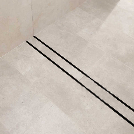 Close-up of a tiled floor with Lauxes Grates Custom shower drain Tile Insert in Midnight Black