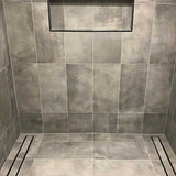 Close-up of a tiled floor with Lauxes Grates Custom shower drain Tile Insert in Midnight Black