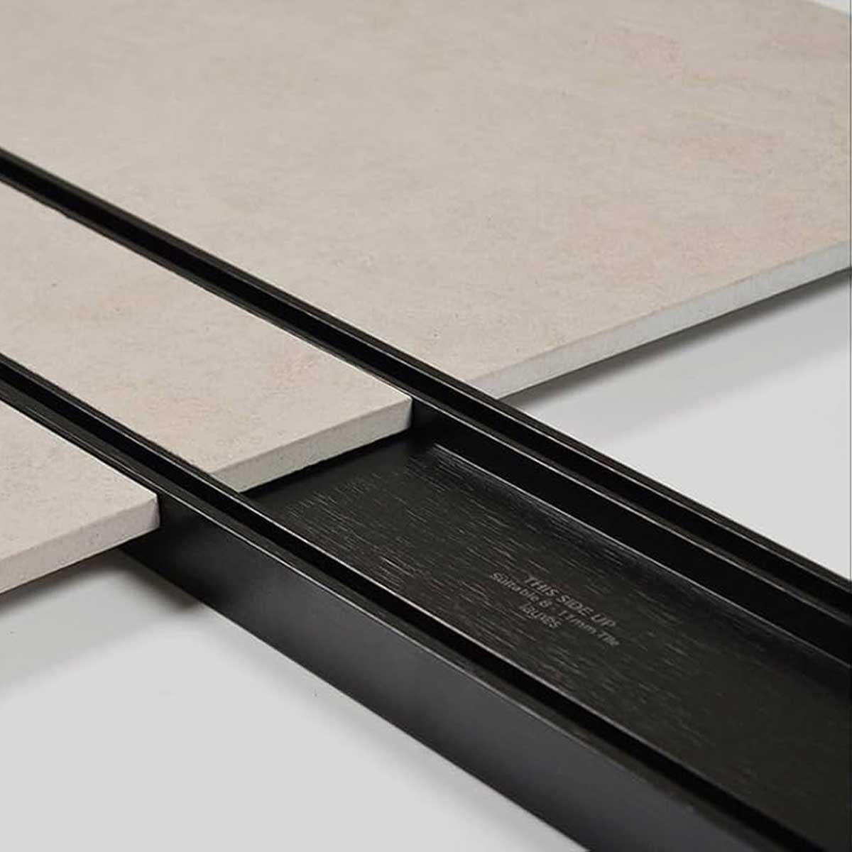 Close-up of a tiled floor with Lauxes Grates Custom shower drain Tile Insert in Midnight Black